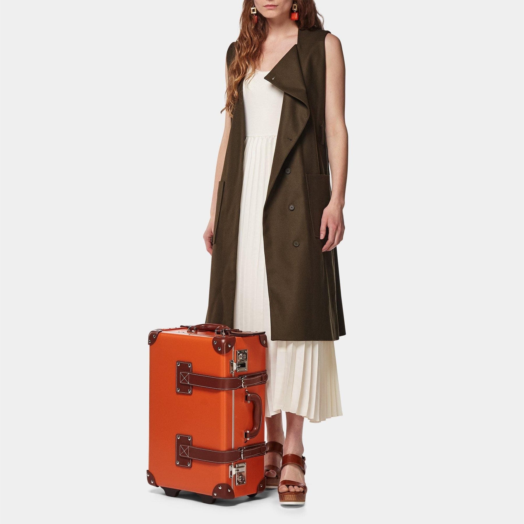 Model with the carry-on Anthropologist leather suitcase in orange