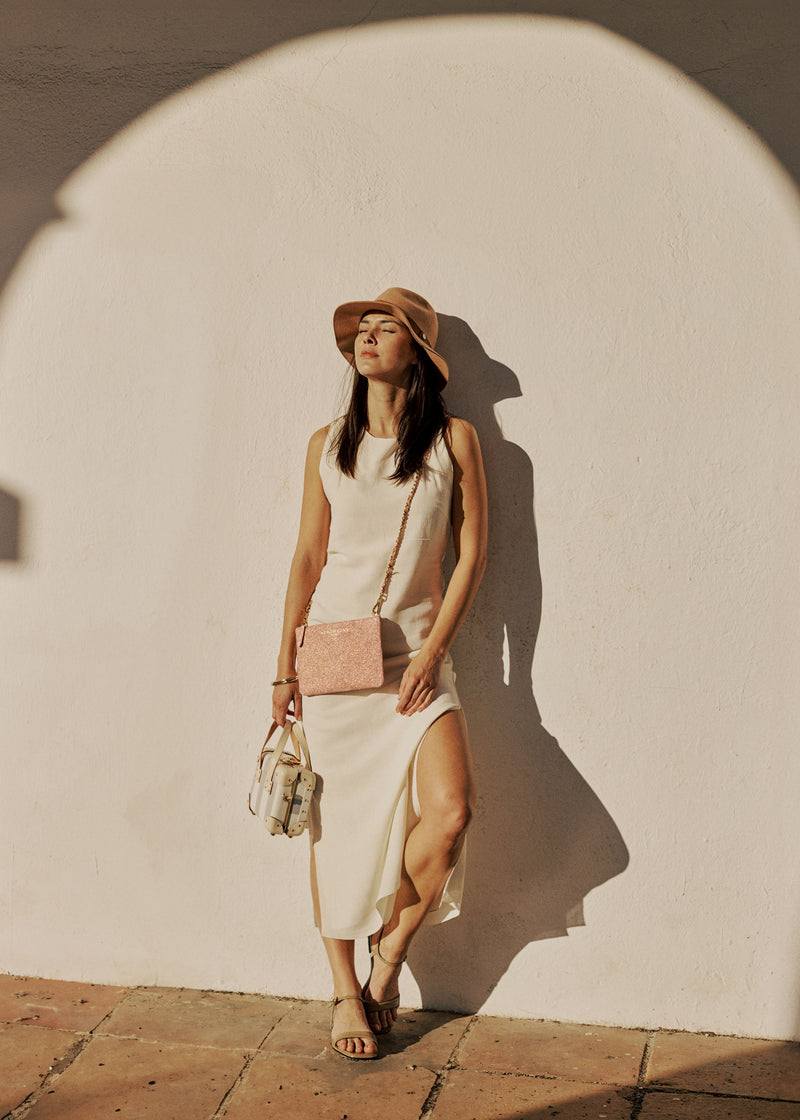 Lifestyle image of model with the Navigator crossbody bag in desert glitter and the mini Illustrator in blue