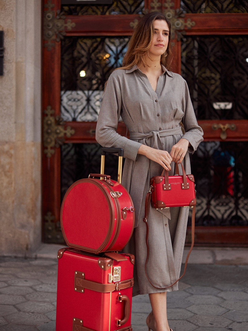 Lifestyle image of model with The Diplomat leather suitcases in red