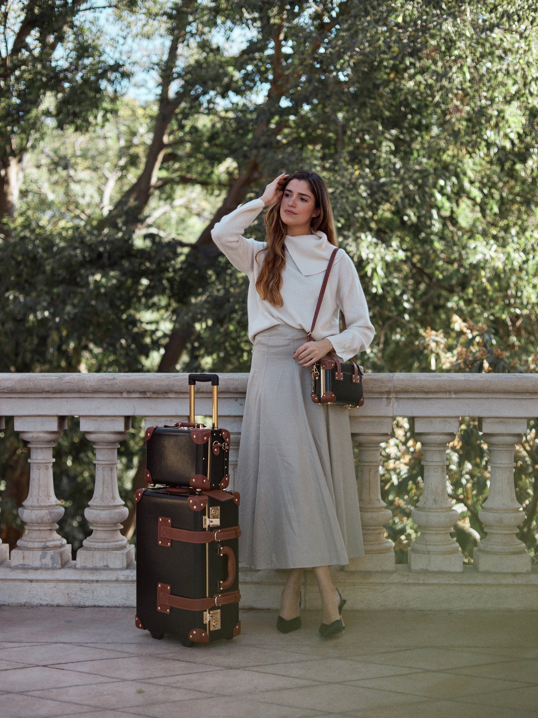 Lifestyle image of model with The Diplomat leather suitcases in black