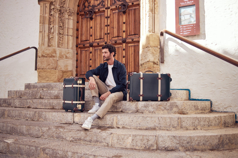 Lifestyle image of male model with The Architect leather suitcases in navy