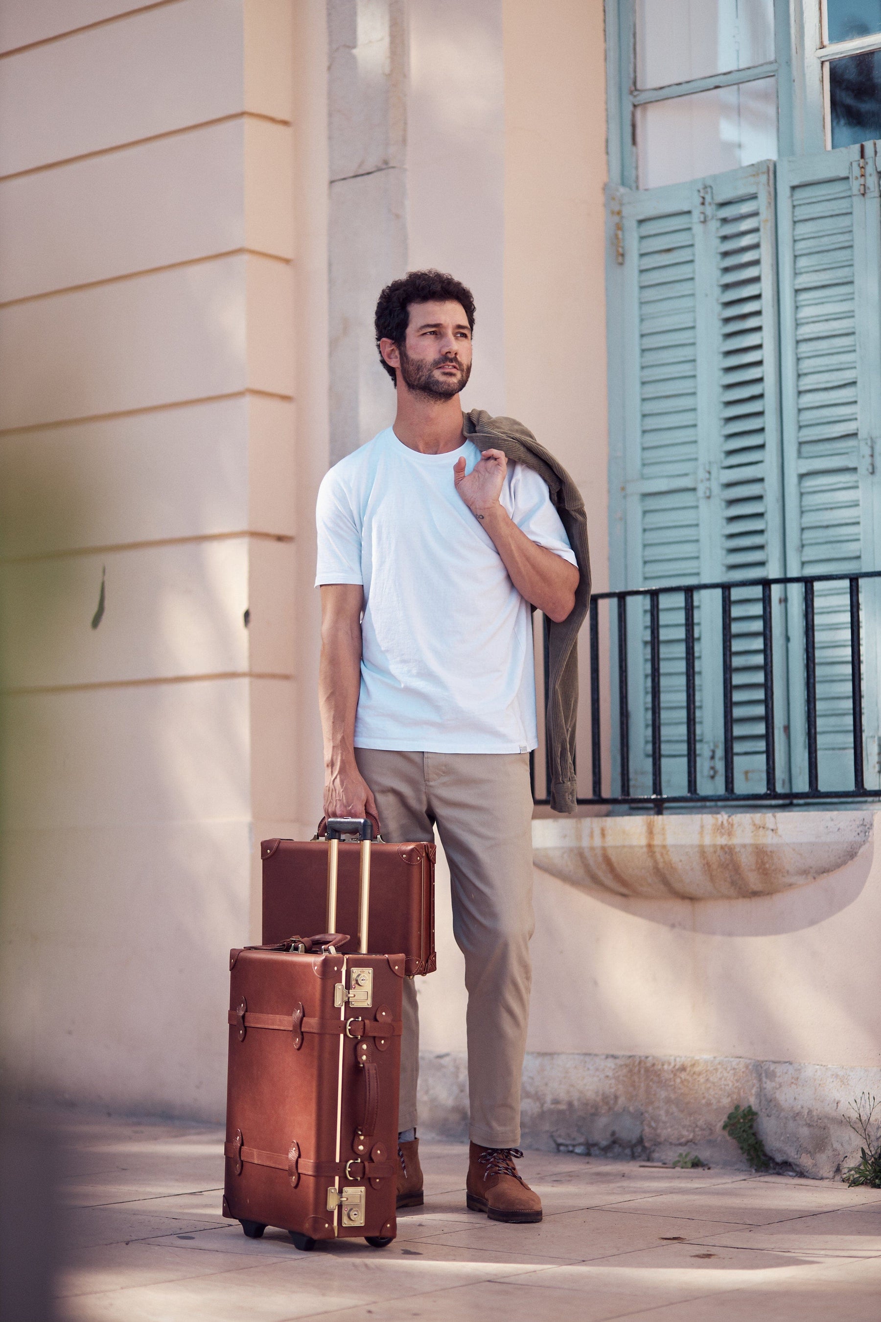 Lifestyle image of male model with The Pioneer leather suitcases in brown