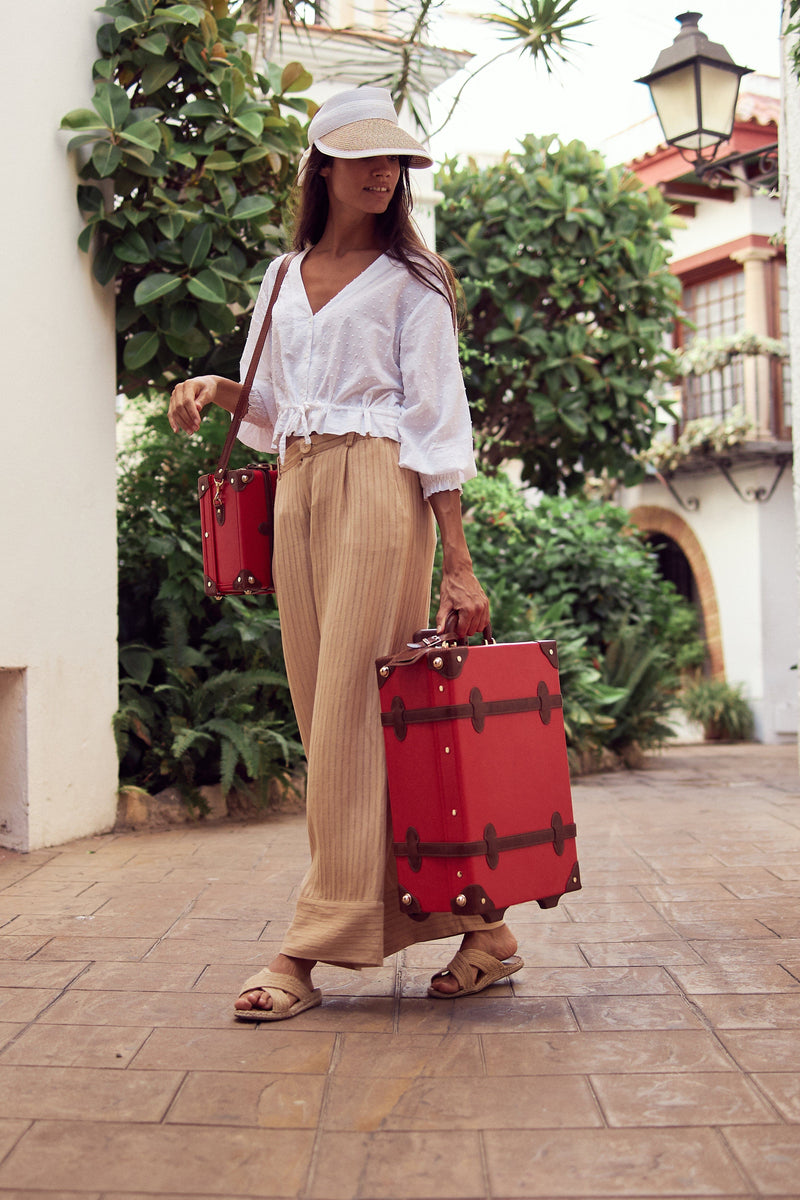 Lifestyle image of model with the Entrepreneur vegan leather suitcases in red