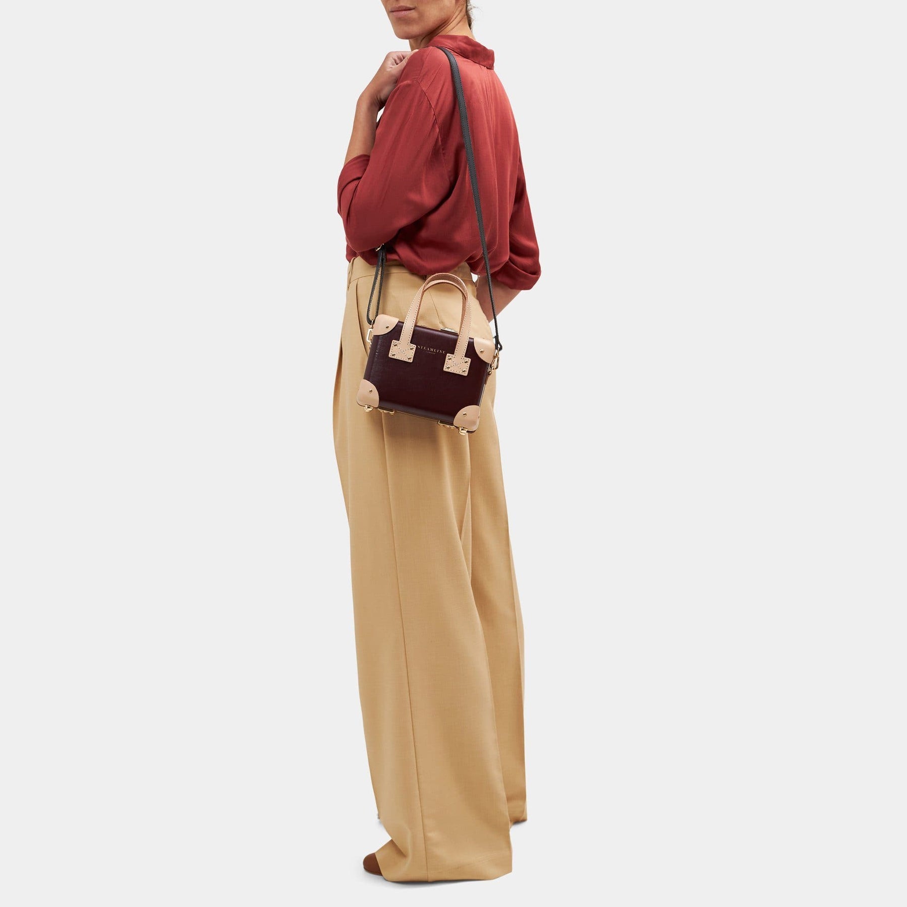 Model with the mini Architect leather suitcase in burgundy with shoulder attachment strap