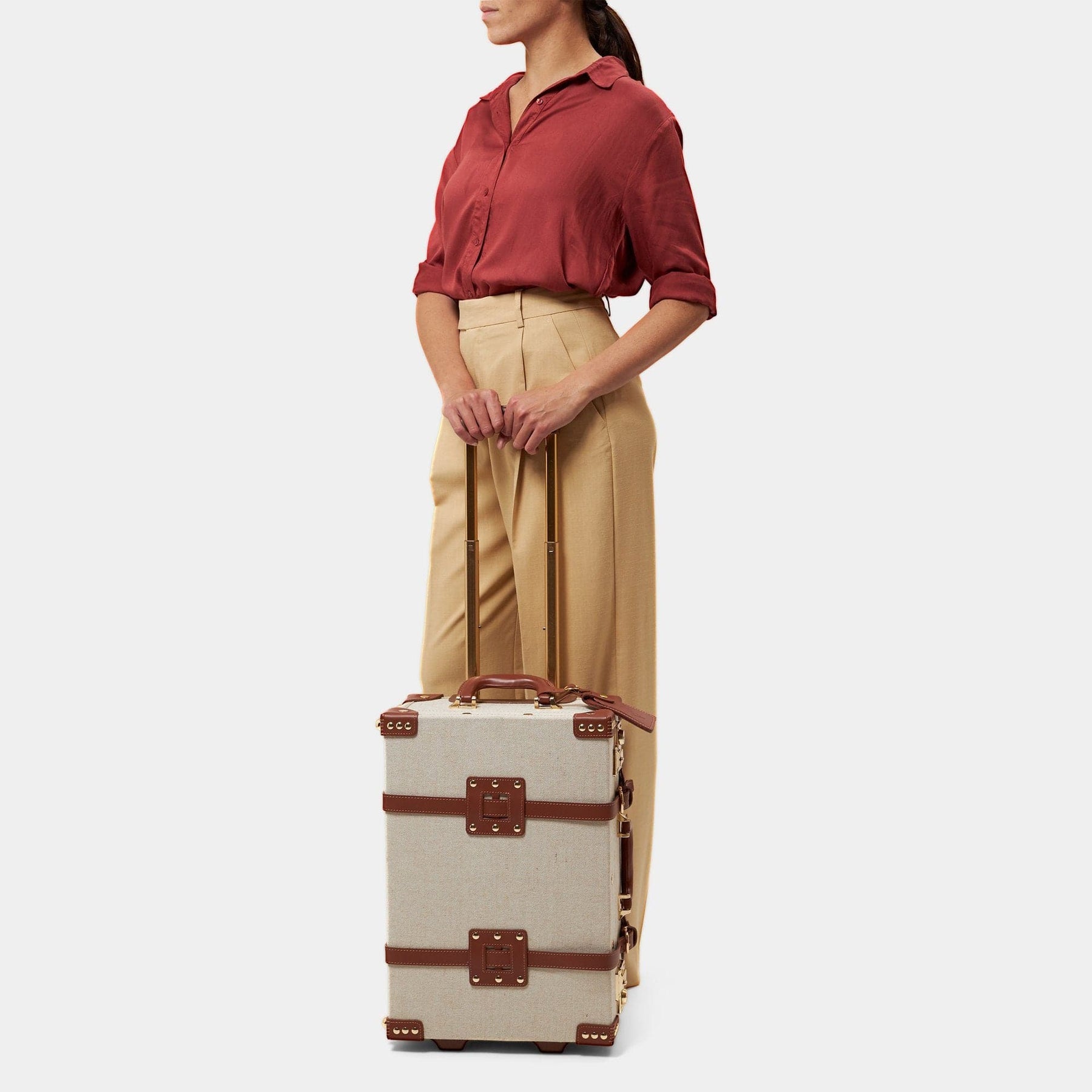 Model with the carry-on Editor linen suitcase with brown trims and raised handle