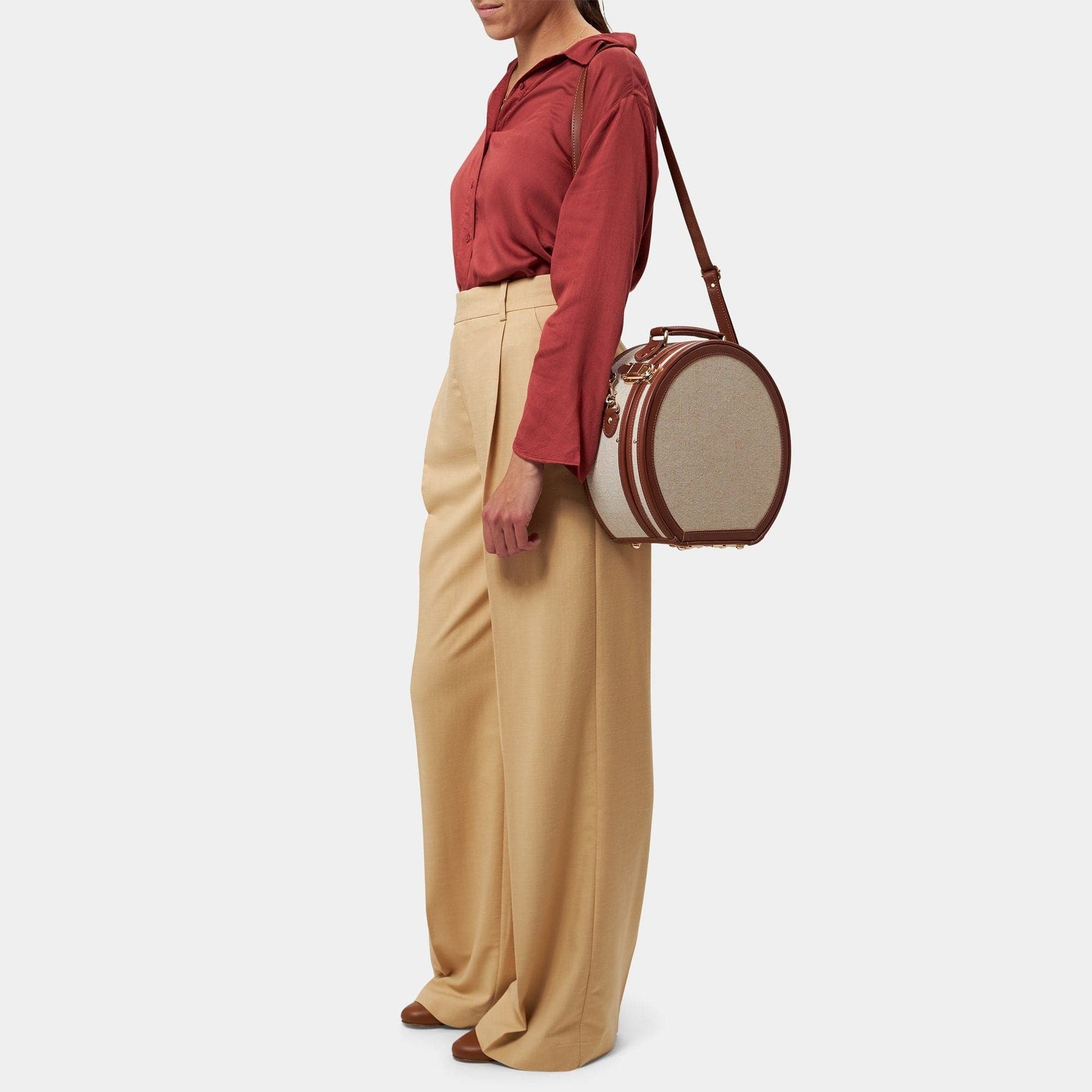 Model with the small hatbox Editor linen suitcase with brown trims and shoulder attachment strap