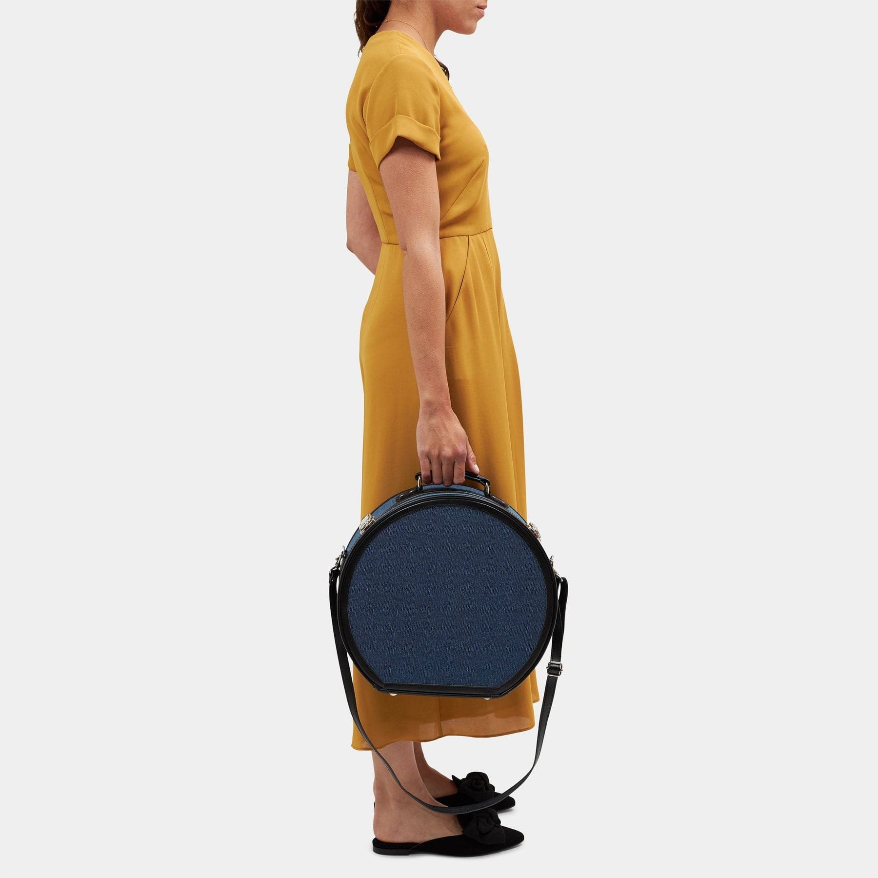 Model with the large hatbox Editor linen suitcase with navy body, black trims and shoulder attachment strap