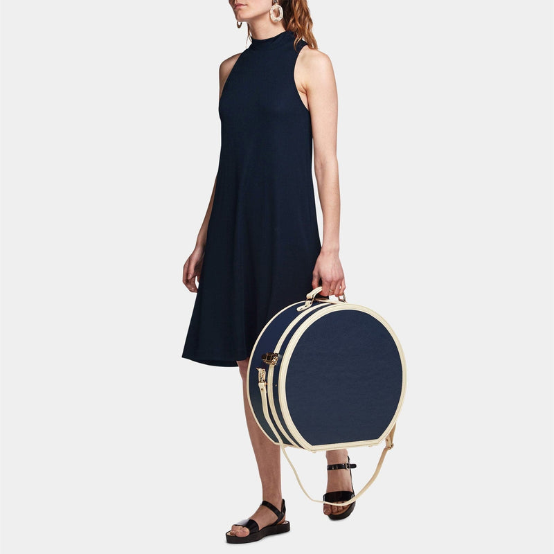 Model  with the deluxe hatbox Entrepreneur vegan leather suitcase in navy with shoulder attachment strap