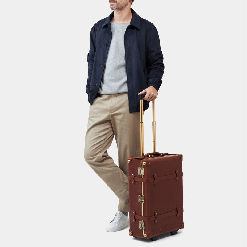 Male model with the carry-on Pioneer leather suitcase in brown with raised handle