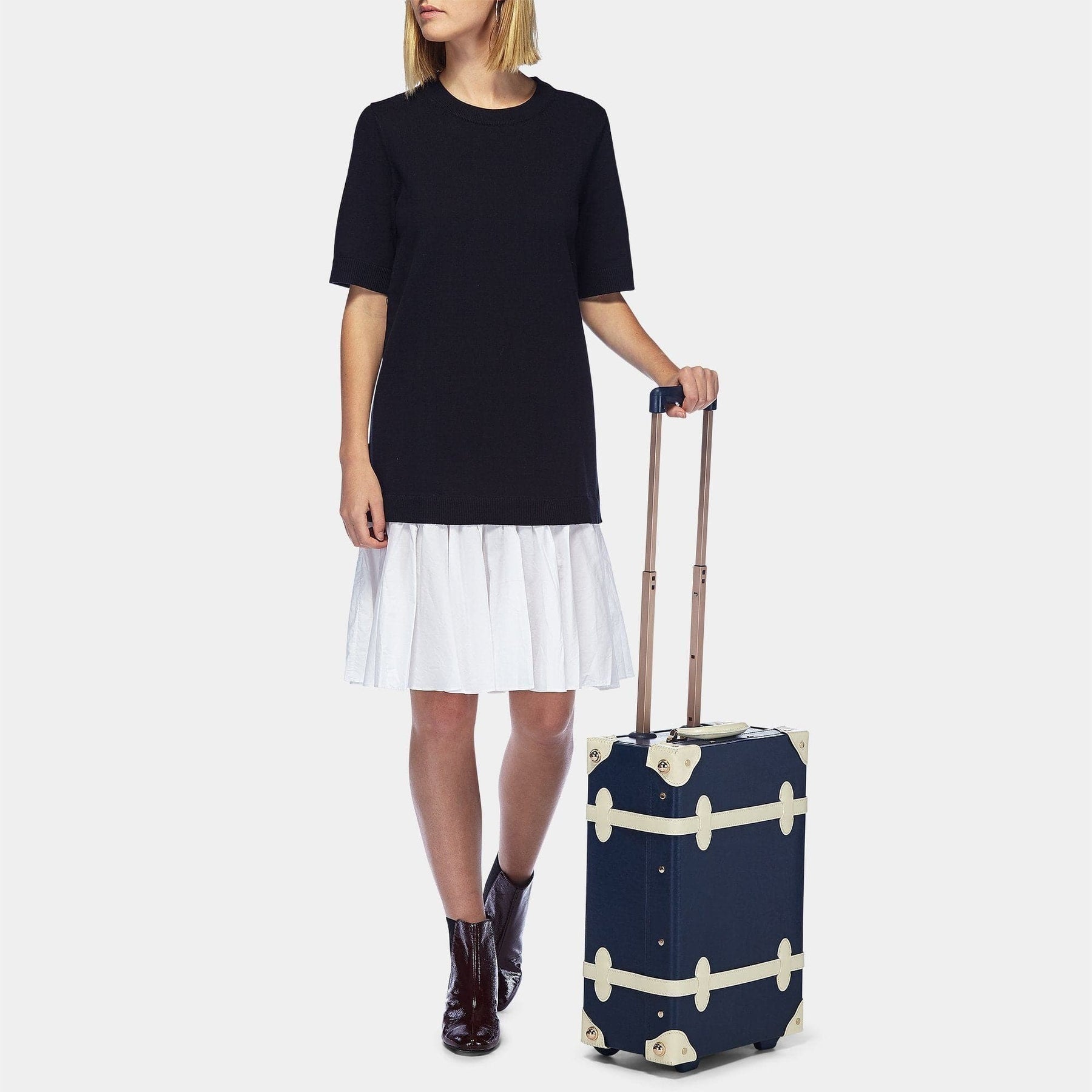 Model with the carry-on Entrepreneur vegan leather suitcase in navy with raised handle