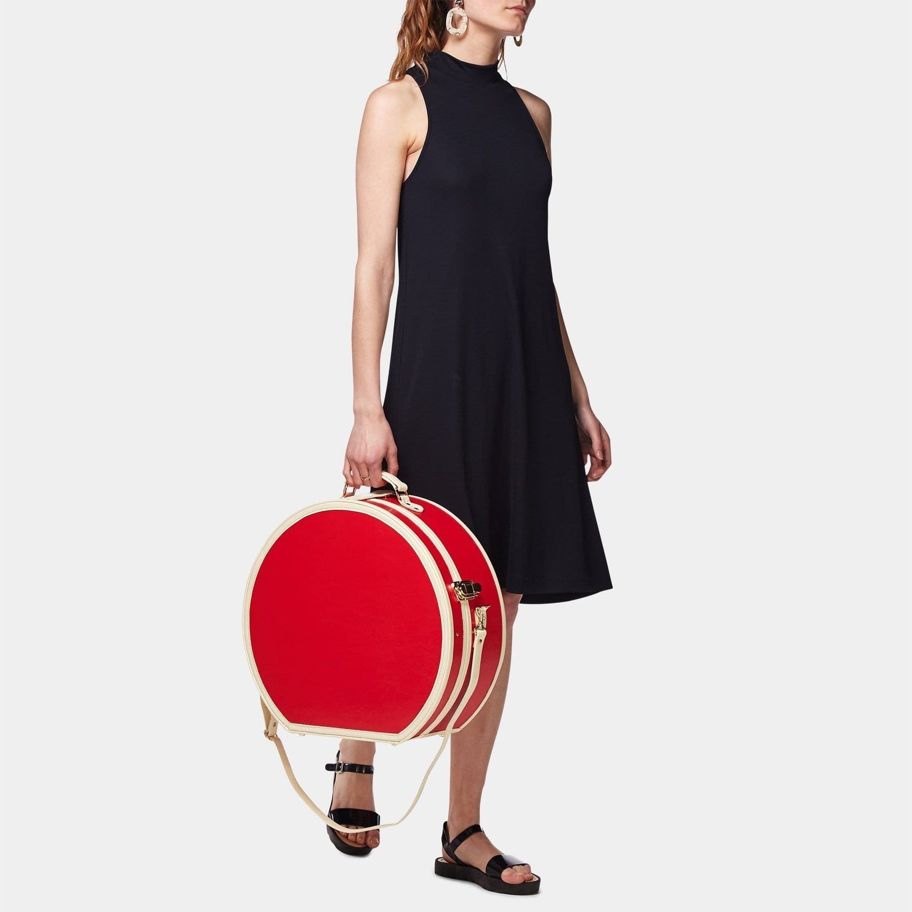 Model  with the deluxe hatbox Entrepreneur vegan leather suitcase in lipstick red with shoulder attachment strap
