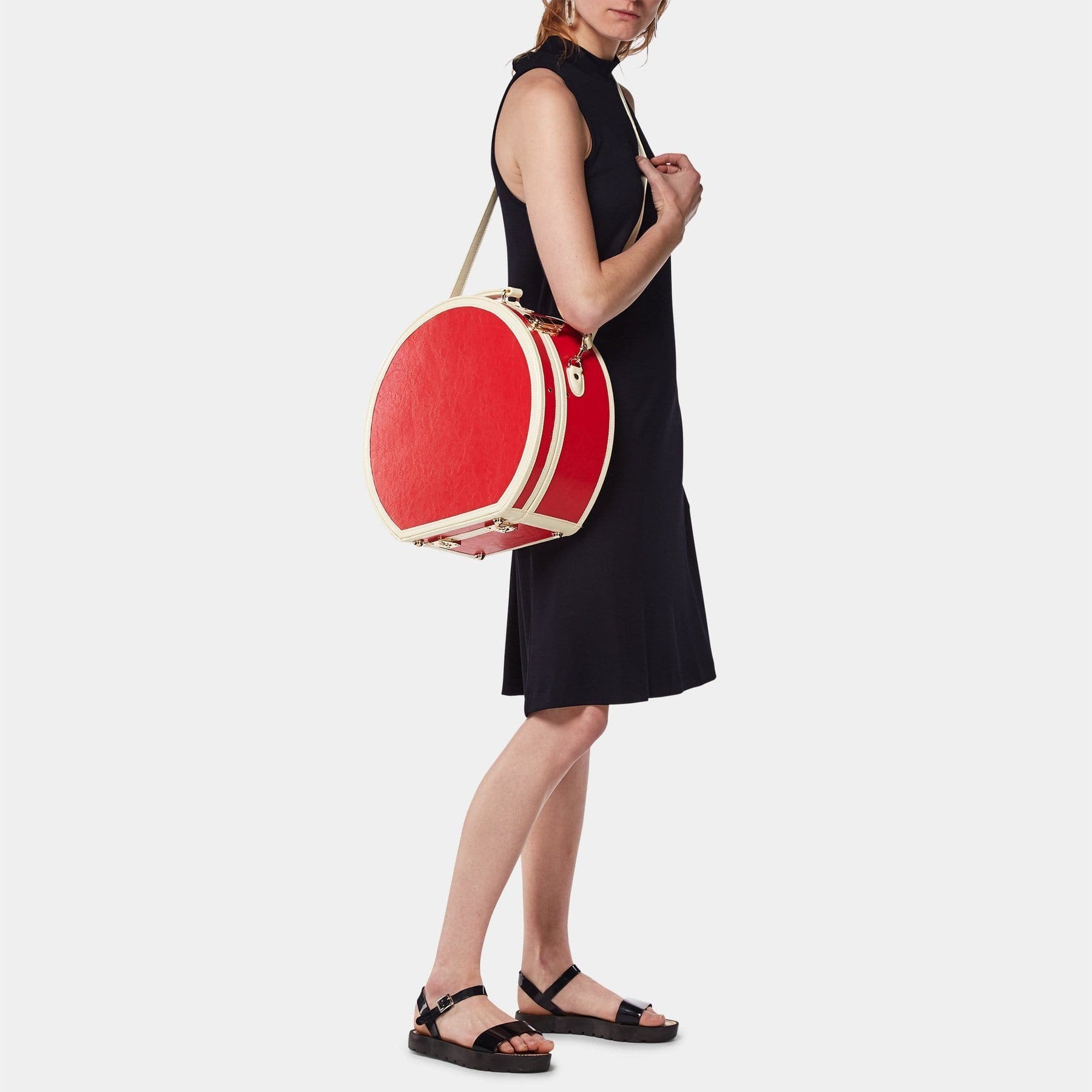 Model with the large hatbox Entrepreneur vegan leather suitcase in lipstick red with shoulder attachment strap