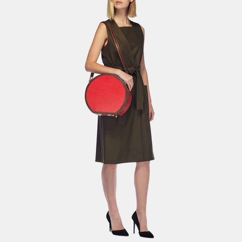 Model with the small hatbox Entrepreneur vegan leather suitcase in red with shoulder attachment strap