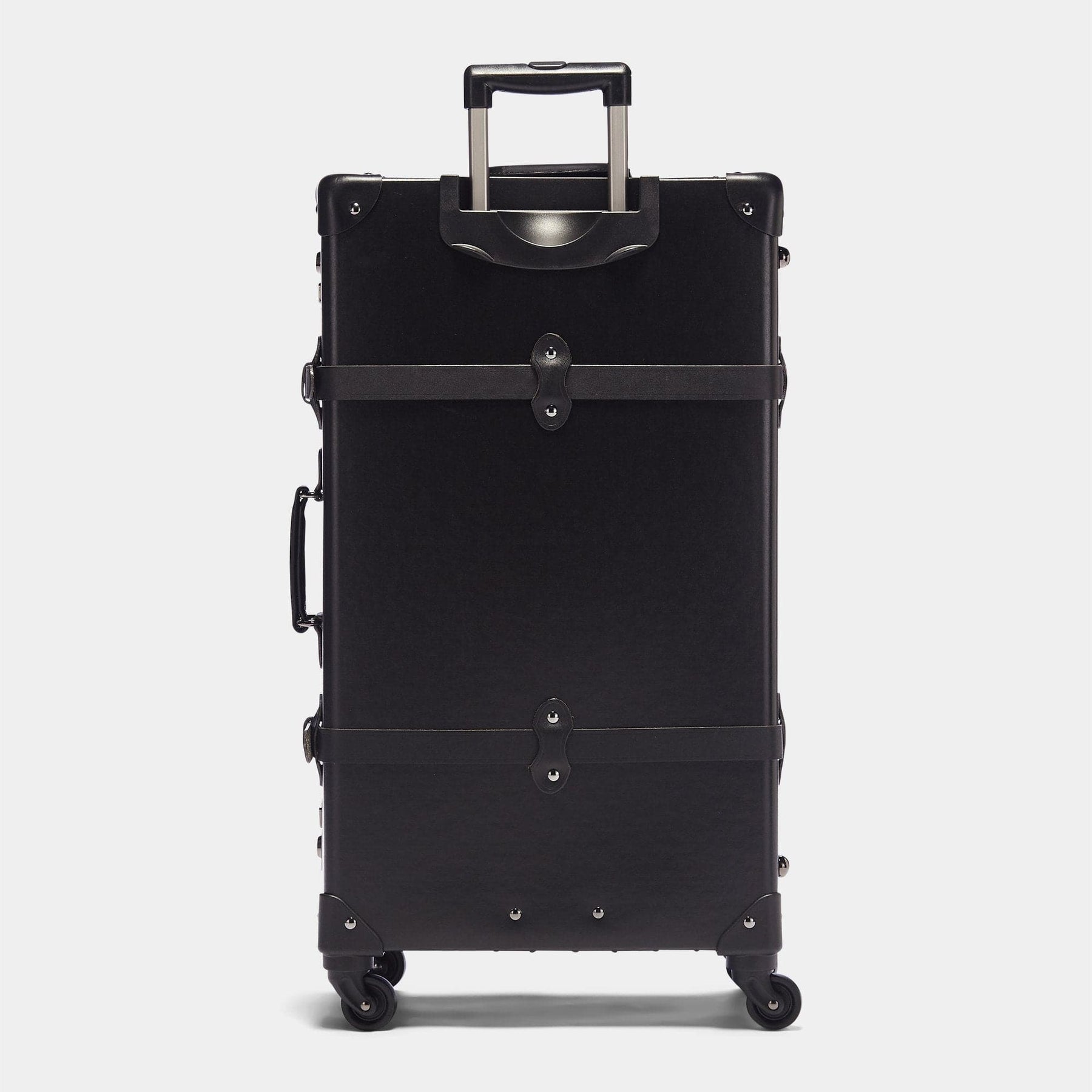 Back product view of the check-in spinner Industrialist fibreboard suitcase in black with raised handle