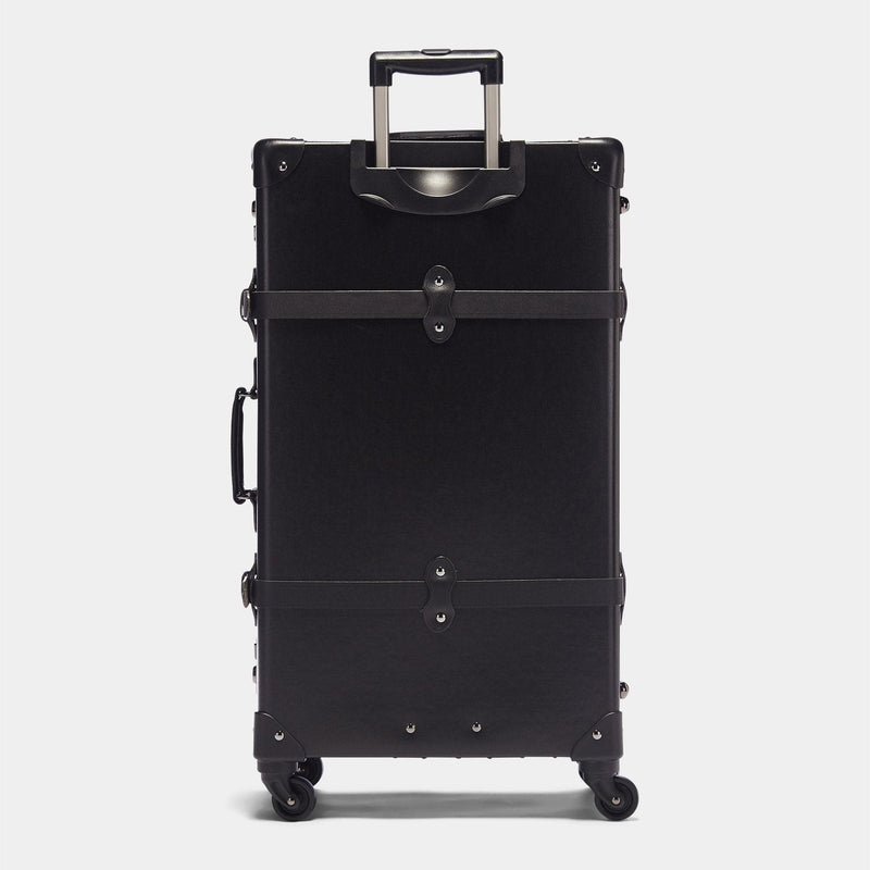 Back product view of the check-in spinner Industrialist fibreboard suitcase in black with raised handle