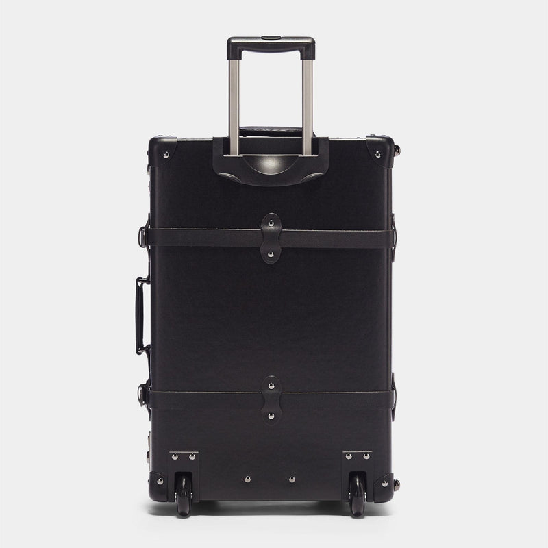 Back product view of the stowaway Industrialist fibreboard suitcase in black with raised handle
