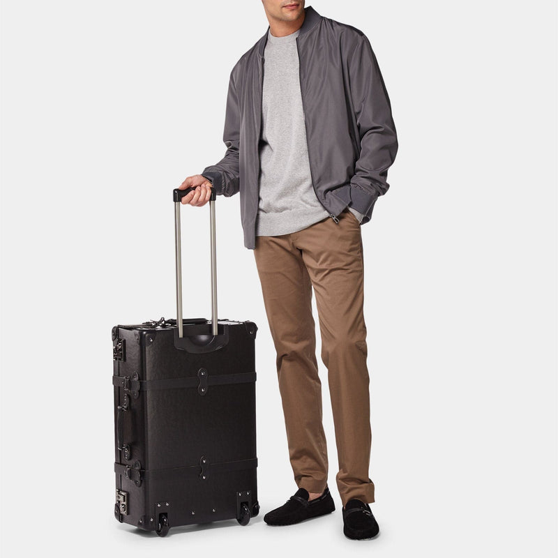Male model with the stowaway Industrialist fibreboard suitcase in black with raised handle