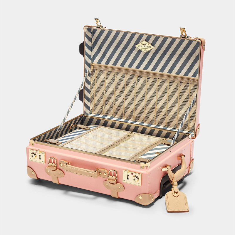 Open product view of the carry-on Correspondent fibreboard suitcase in pink with blue and white stripe  print lining and tan leather luggage tag