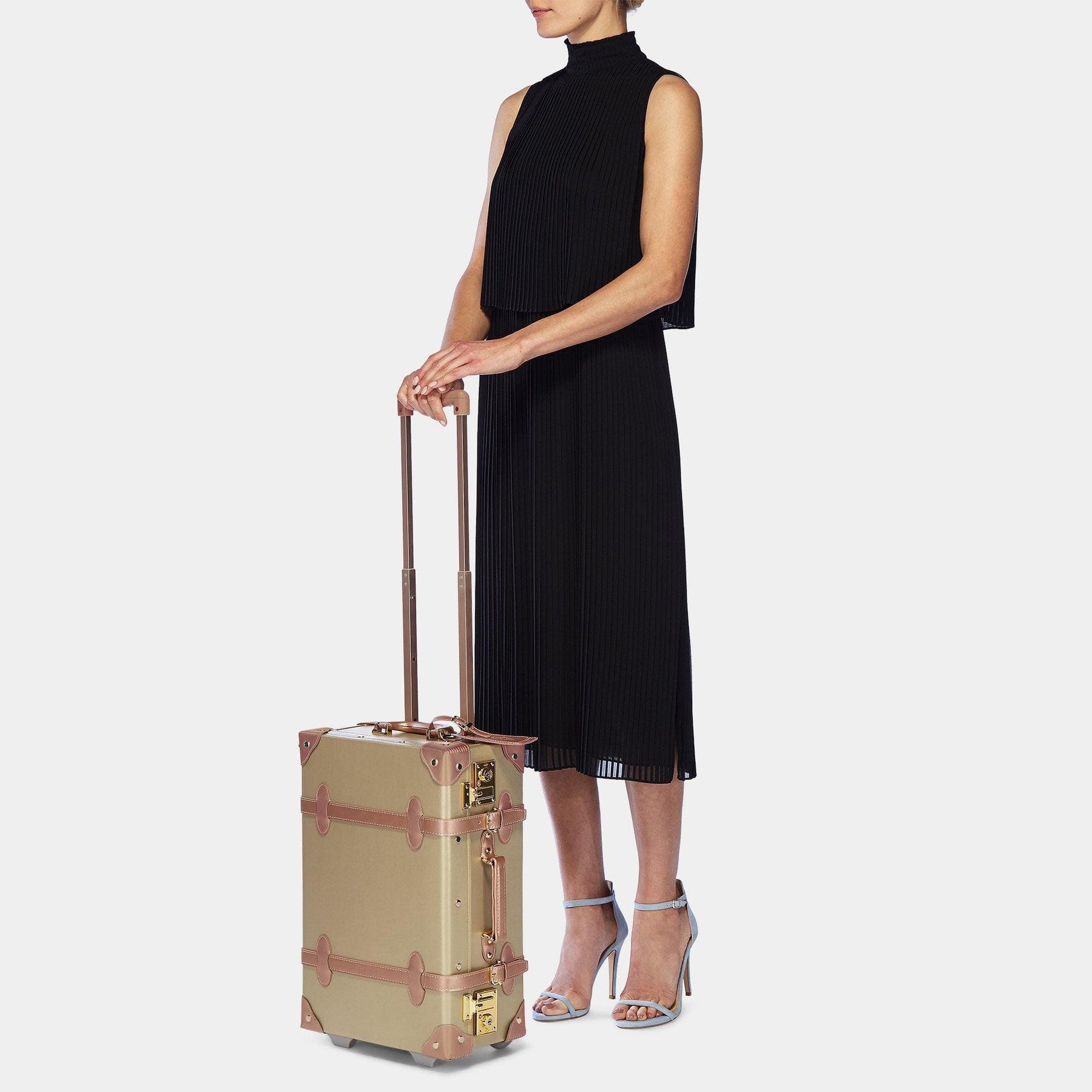 Model with the carry-on Alchemist vegan leather suitcase in gold with raised handle