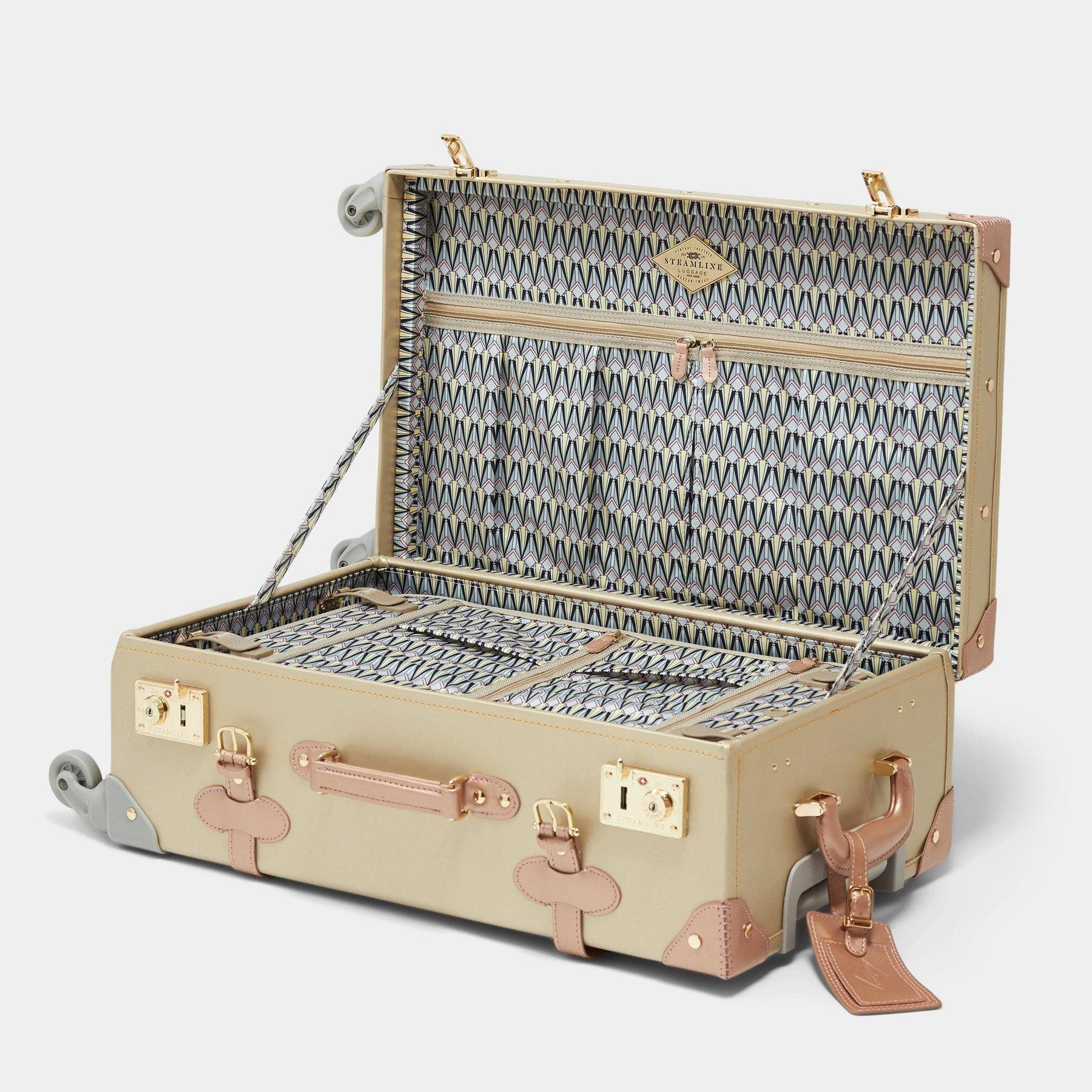 Open product view of the check-in spinner Alchemist vegan leather suitcase in gold with art-deco print lining and blush vegan leather luggage tag