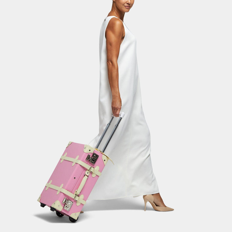 Model with the carry-on Entrepreneur vegan leather suitcase in pink with raised handle